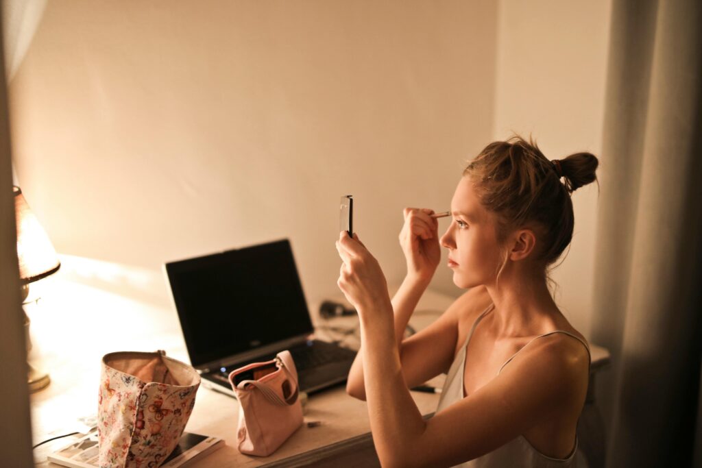 a woman doing her makeup in front of the mirror